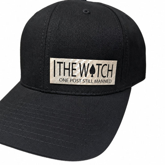 Close-up of The Watch leatherette patch on a black hat, with One Post Still Manned lettering.