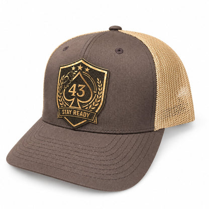 Angled view of a brown and tan Richardson 112 hat with a laser-engraved Stay Ready patch featuring a raven and 43 spade.
